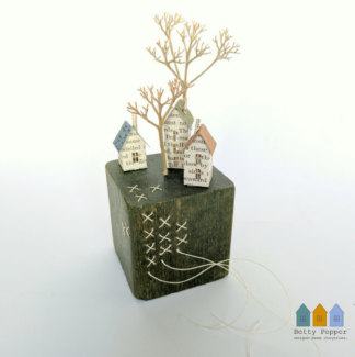 Miniature paper houses handcrafted from faded vintage book covers and book pages, perched on a green vintage child's wooden building block base. This delicate sculpture features hand stitching into the block in a contrast thread. Handmade by British artist Betty Pepper.