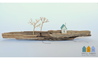 Miniature paper house handcrafted from faded vintage book covers and book pages, perched on a natural driftwood base. This delicate sculpture features subtle, neutral tones and natural materials by British artist Betty Pepper.