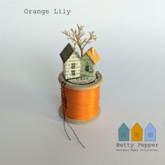 Miniature paper house handcrafted from repurposed book pages perched on a vintage wooden cotton reel wound with orange thread. A tiny thread ladder hangs down the side of the reel. By British artist Betty Pepper.