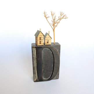 Miniature paper houses handcrafted from faded vintage book covers and book pages, perched on a vintage printer’s wooden letter ‘D’ block base. A tiny thread ladder in a contrast colour hangs down the side of the block. By British artist Betty Pepper.